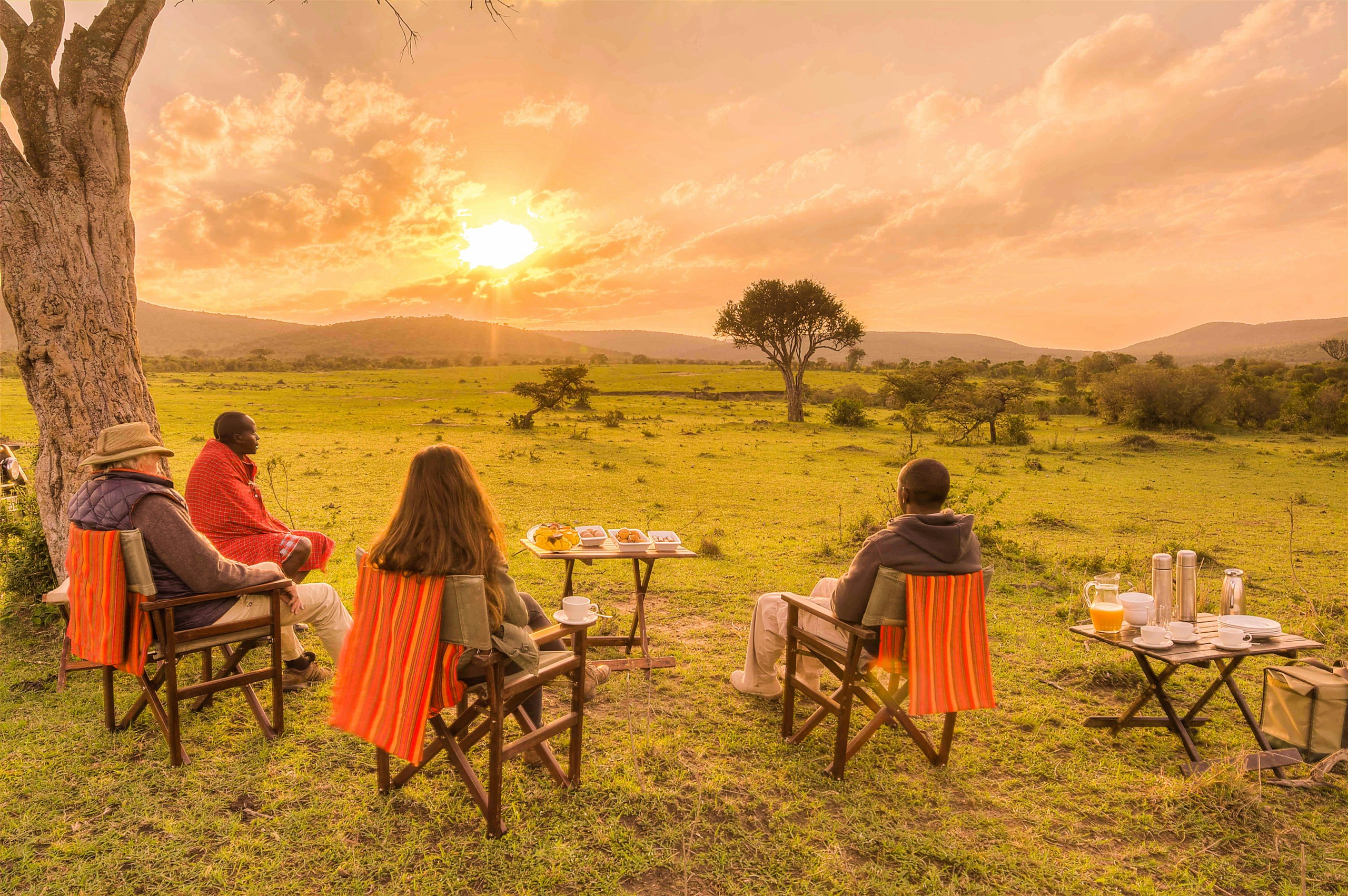 Travelers seated on the savanna at golden light